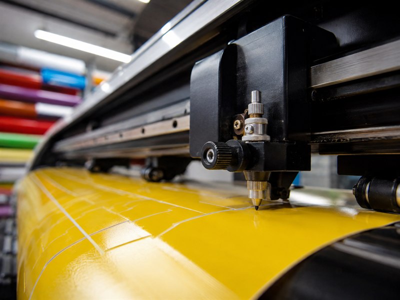 Plotter de recorte cortando vinil amarelo na gráfica